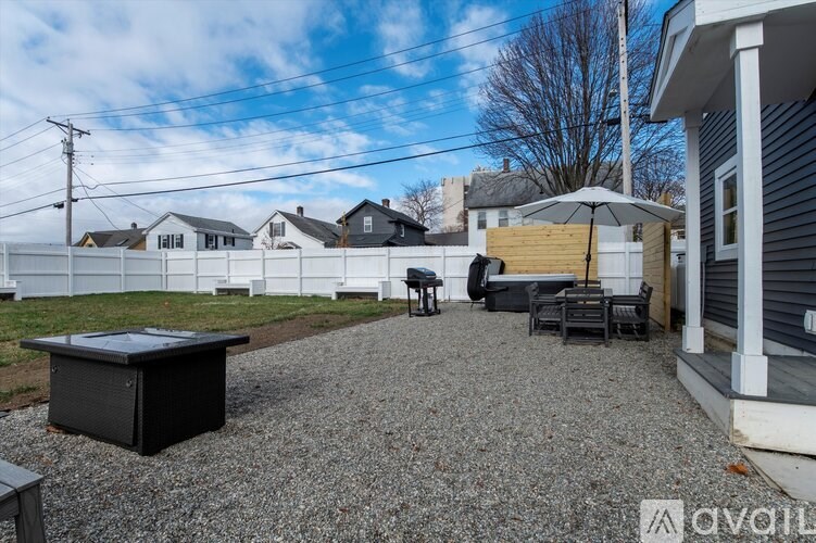 A backyard with a gravel area, a black box, and a patio with furniture.