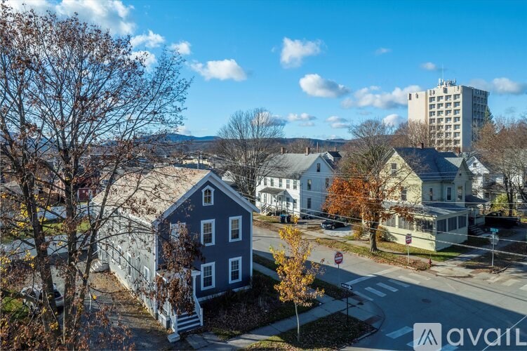 A blue house with a white fence in front of a street.