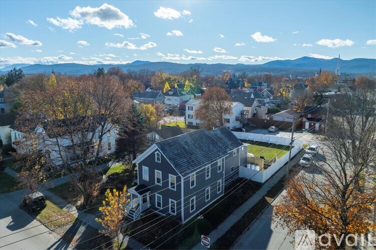A house with a grey roof is surrounded by trees with yellow leaves.