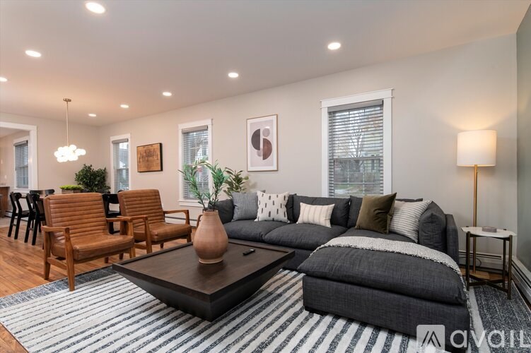 A living room with a grey couch, a brown chair, a coffee table, and a lamp.