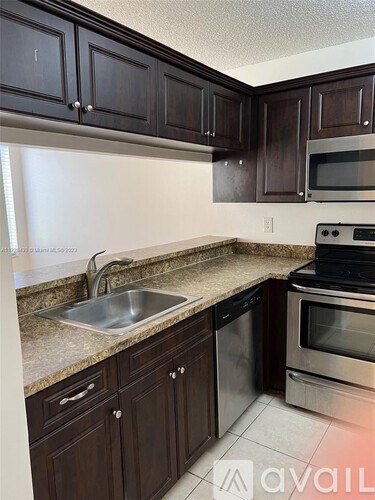 A kitchen with dark brown cabinets and stainless steel appliances.