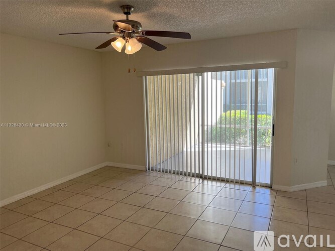 A room with a ceiling fan and sliding glass doors.
