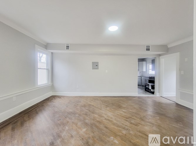 A spacious room with wooden flooring and white walls.