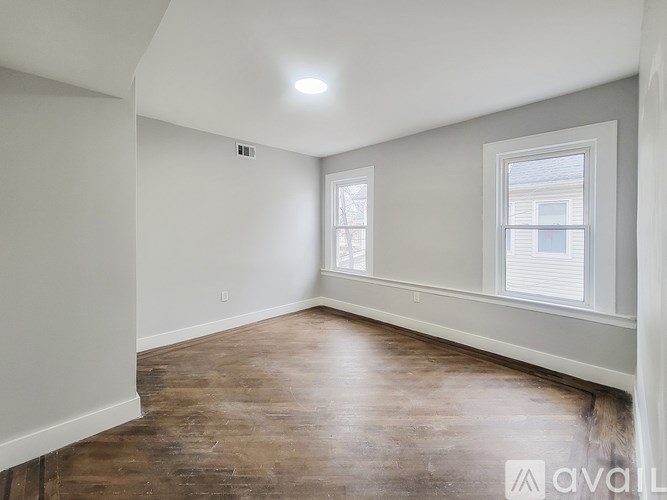 A room with wooden flooring and a window with blinds.