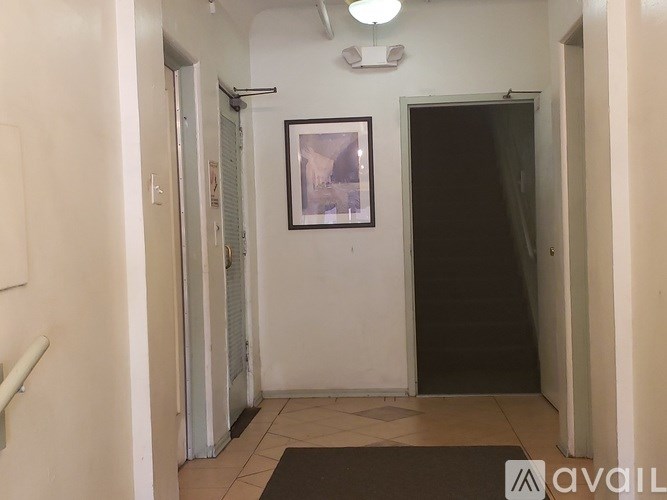 A hallway with a door on the right and a picture on the wall.