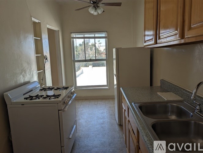 A kitchen with a stove, sink, and window.