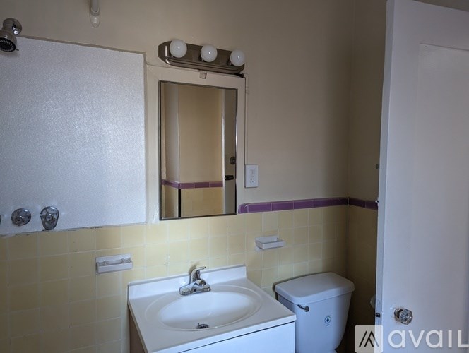 A bathroom with a sink, toilet, and mirror.