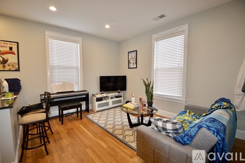 A living room with a grey couch and a black piano.