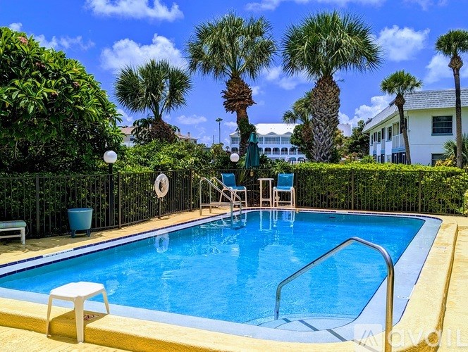 A pool surrounded by greenery and palm trees.