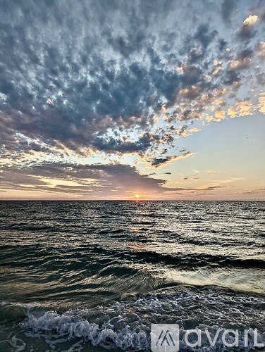 A sunset over the ocean with waves crashing in the foreground.