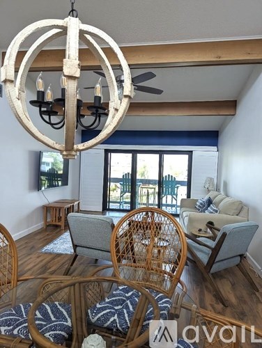 A living room with a grey couch, a wooden chair and a hanging light fixture.