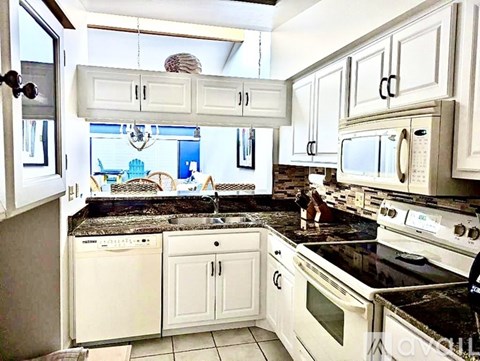 A kitchen with white cabinets and appliances.