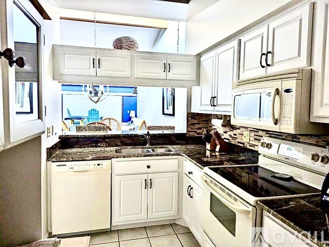A kitchen with white cabinets and appliances.