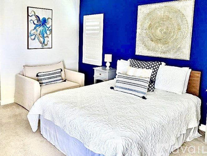 A bedroom with a white bed and a blue wall.