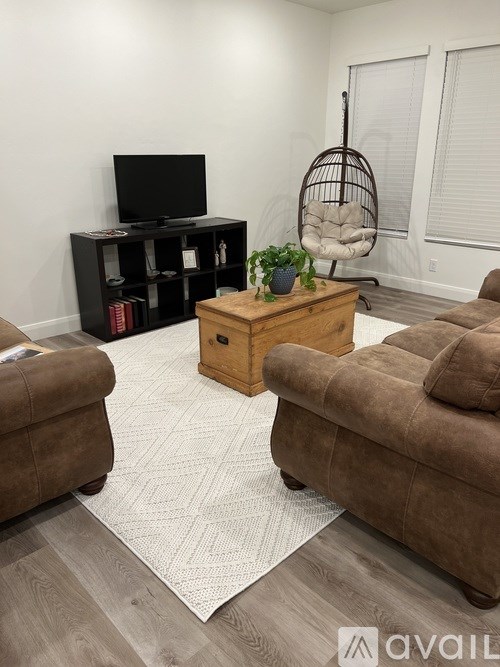 A living room with a brown couch, a wooden coffee table, and a TV on a black stand.