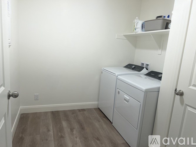 A small room with a white door, a white cabinet with a drawer and a shelf above it.