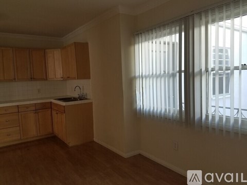 A kitchen with wooden cabinets and a window with blinds.