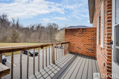 A balcony with a wooden railing and a brick wall.