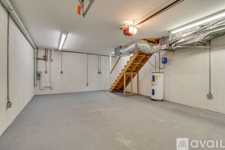 A spacious room with a staircase, white walls, and a concrete floor.
