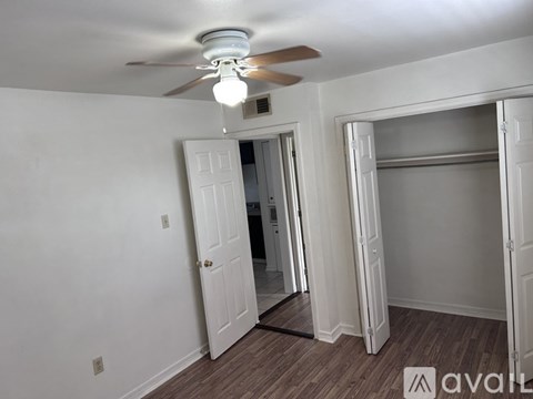 A room with a ceiling fan and a mirrored doorway.