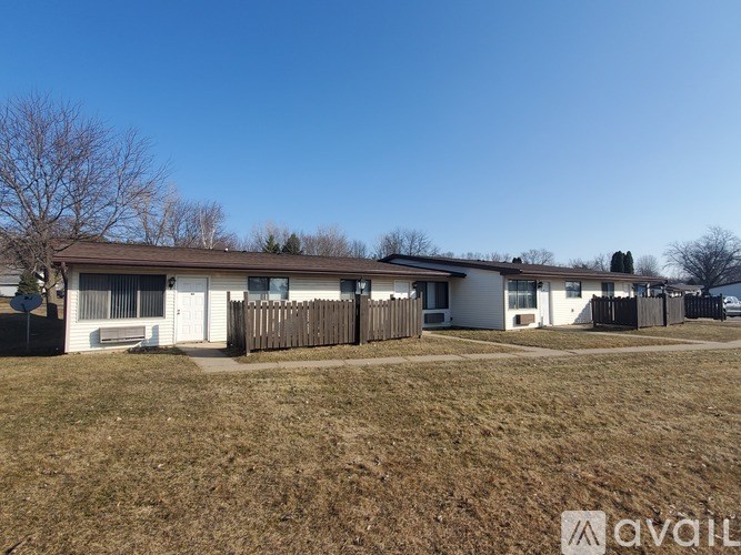 A house with a brown roof and white walls is surrounded by a wooden fence.