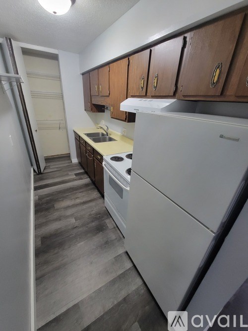 A kitchen with white appliances and wooden cabinets.
