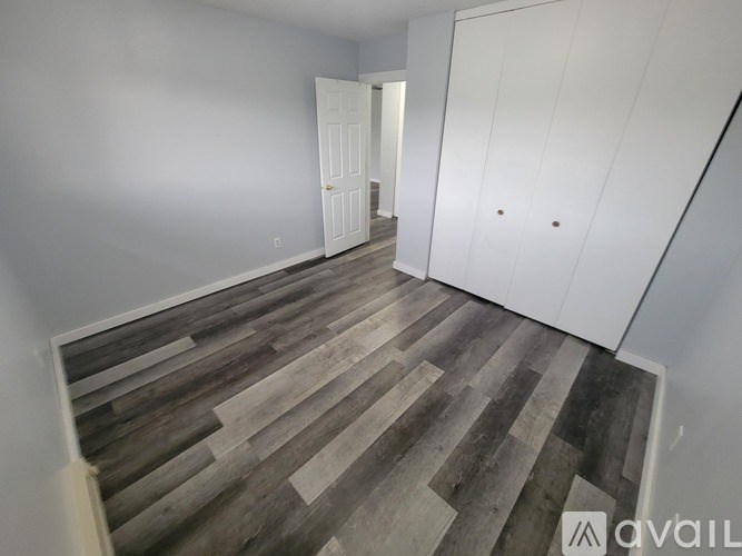 A room with wooden flooring and white walls.