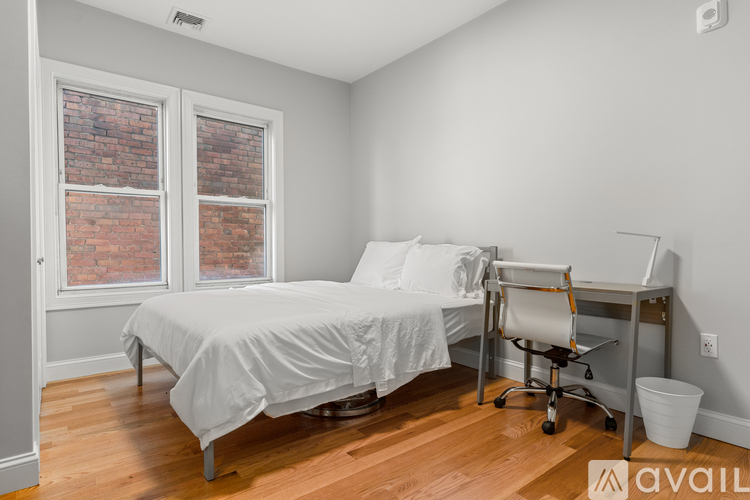 A bedroom with a large bed and a desk with a chair.
