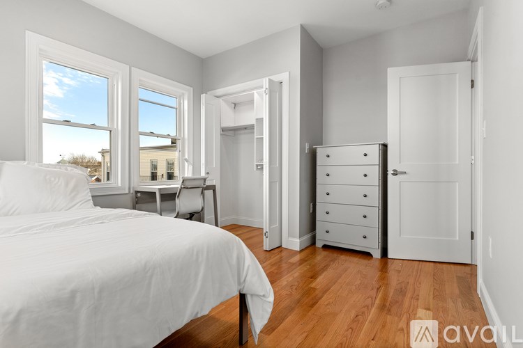 A bedroom with a large bed and a desk with a chair.