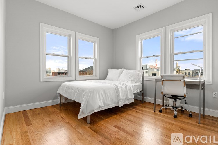 A bedroom with a bed, desk, and chair.
