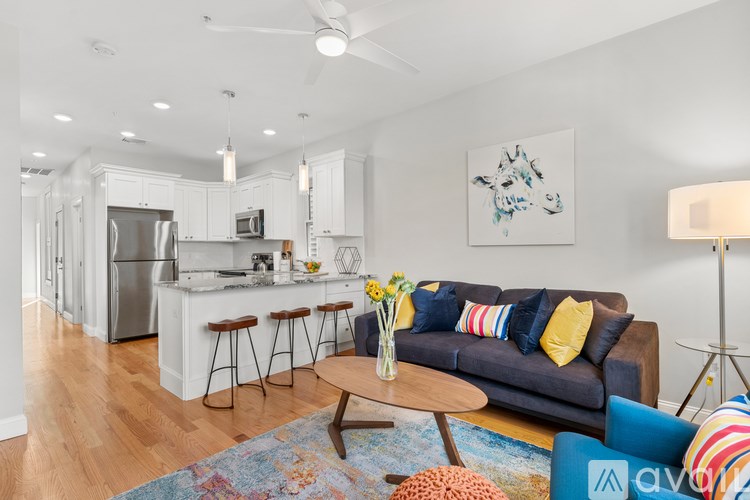 A modern kitchen with a bar and a blue couch with yellow pillows.