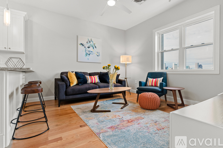 A living room with a grey couch and a wooden stool.