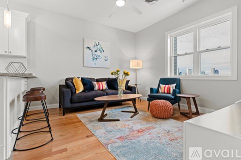 A living room with a grey couch and a wooden stool.