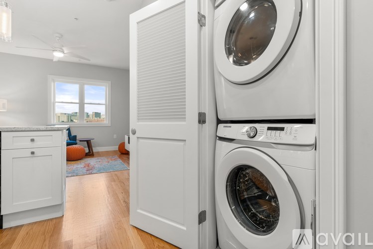 A white washing machine is in a laundry room with a door open.
