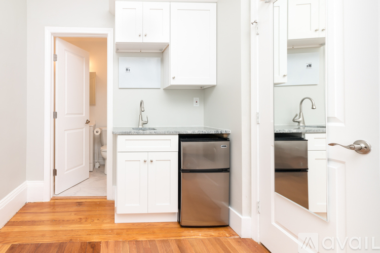 A kitchen with white cabinets and a wooden floor.