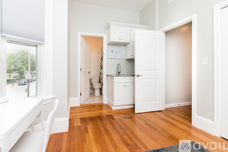 A kitchen with white cabinets and a wooden floor.