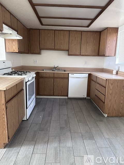 A kitchen with wooden cabinets and a white stove top oven.