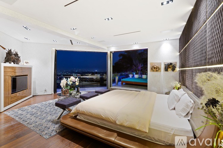 A bedroom with a large bed and a view of the city at night.