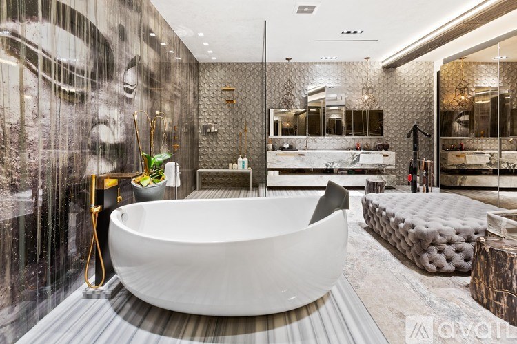 A modern bathroom with a large round bathtub and a mirrored wall.