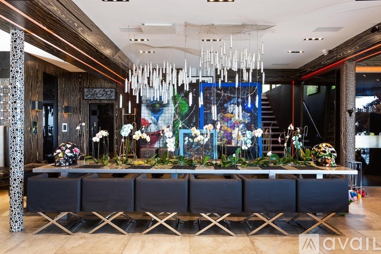 A long table with a black cloth is surrounded by chairs with a large chandelier hanging from the ceiling.