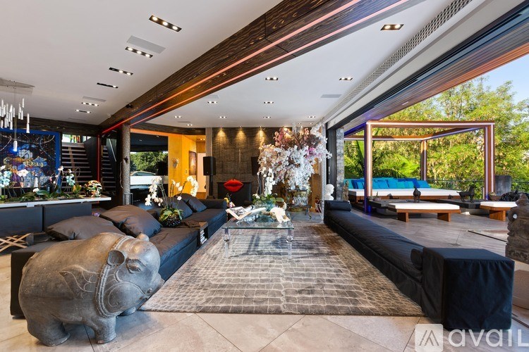 A modern living room with a large black sofa and a stone hippo statue.