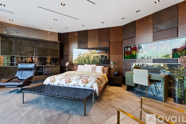 A bedroom with a large bed and a chair.