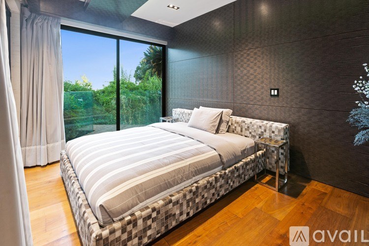 A bedroom with a large bed and a view of the outdoors through the window.