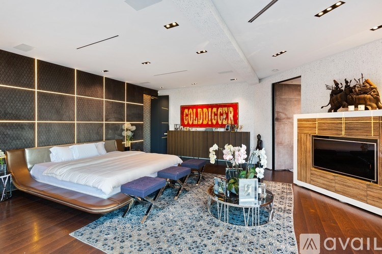 A bedroom with a bed, a chair, a coffee table, and a fireplace.