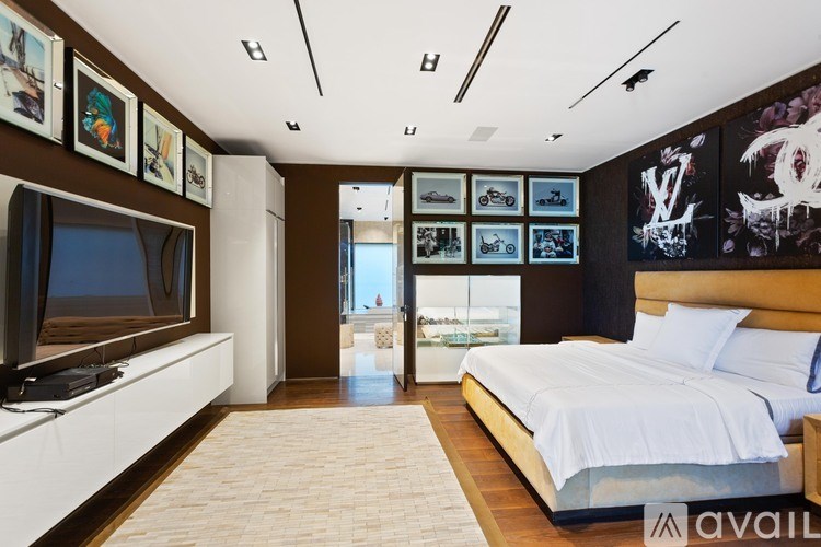 A bedroom with a large bed and a television on the wall.