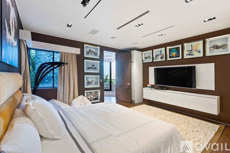 A bedroom with a large bed and a television on the wall.