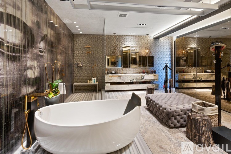 A modern bathroom with a large white bathtub and a grey and white tiled wall.