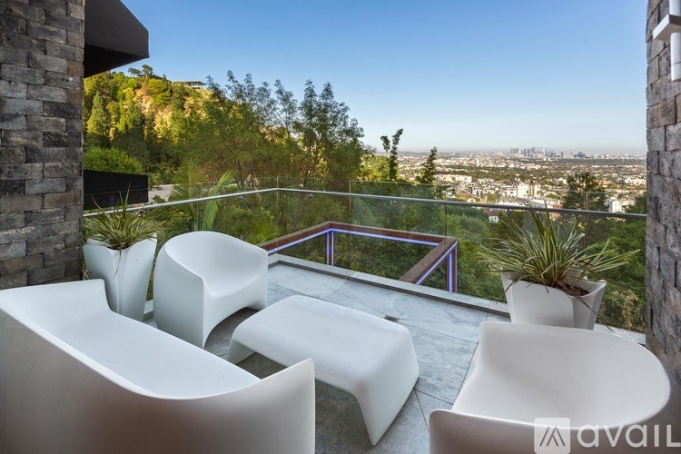 A patio with white chairs and a view of the city.