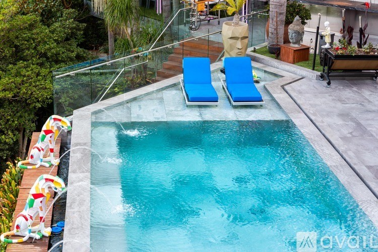 A swimming pool with two lounge chairs and a glass barrier.