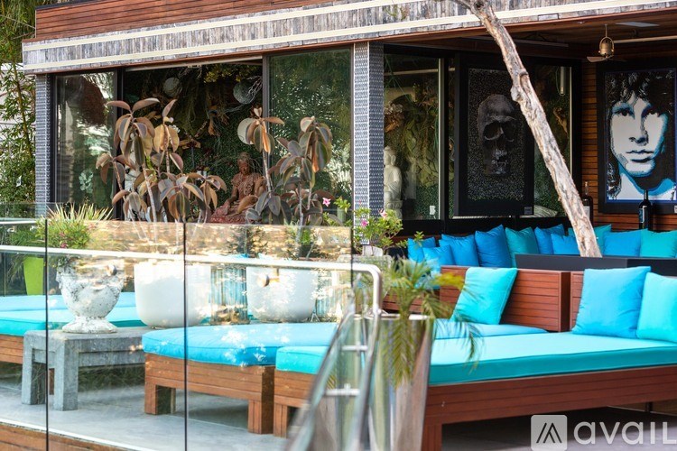 A wooden bench with blue cushions is in front of a glass wall with a picture of a man on it.